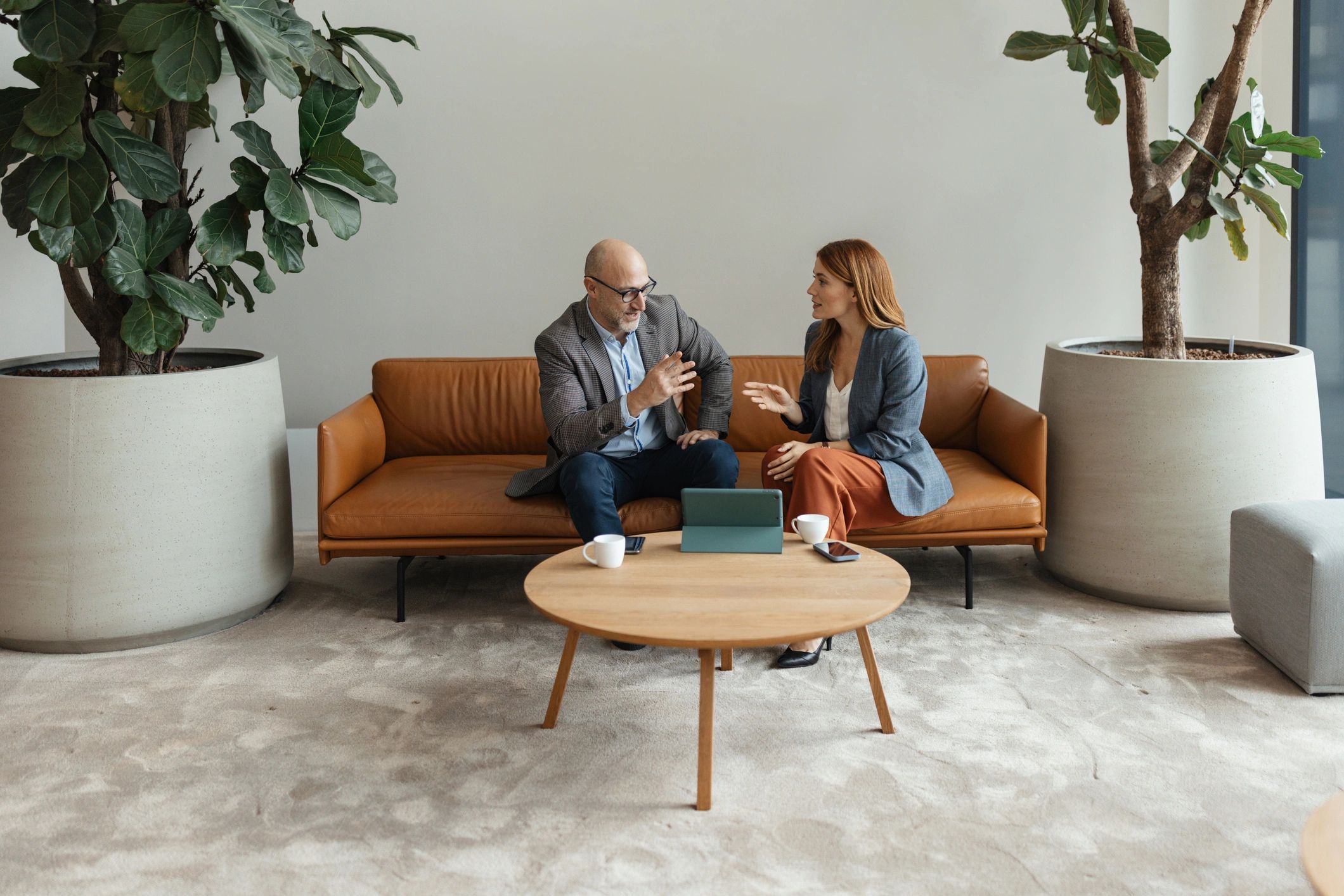 Two professionals in a coaching-style conversation reviewing a tablet